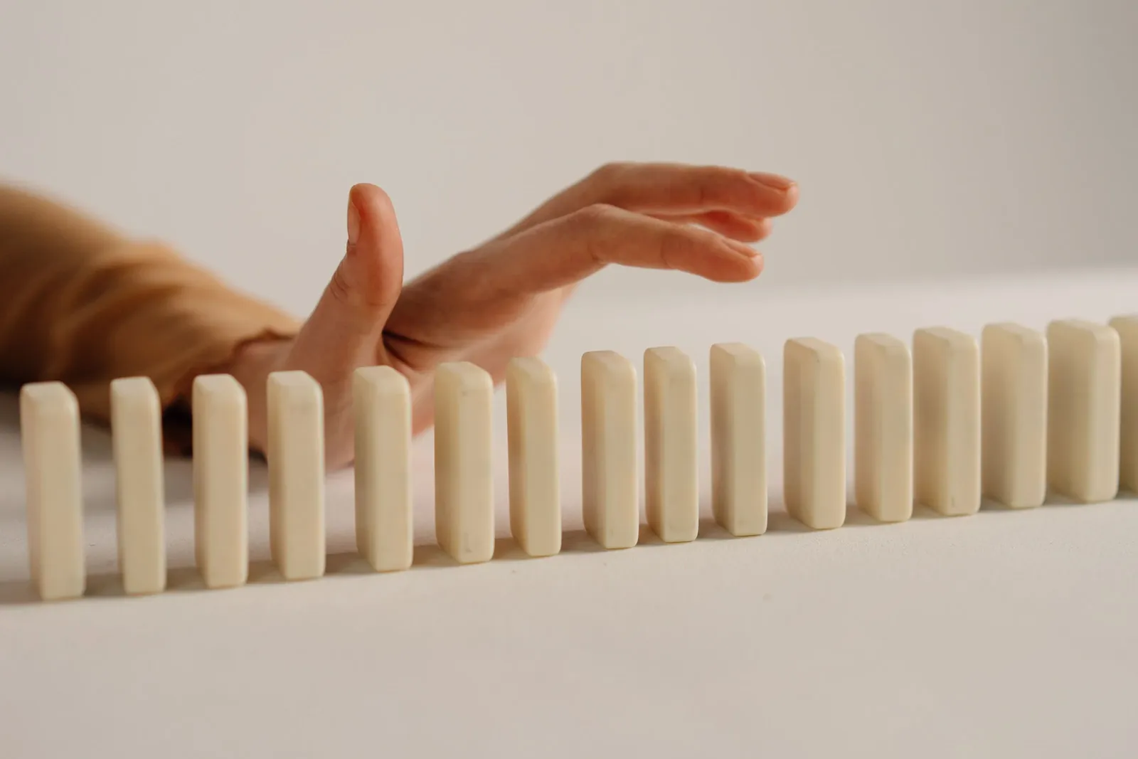 Hand poised to stop falling dominoes, symbolising risk protection and control
